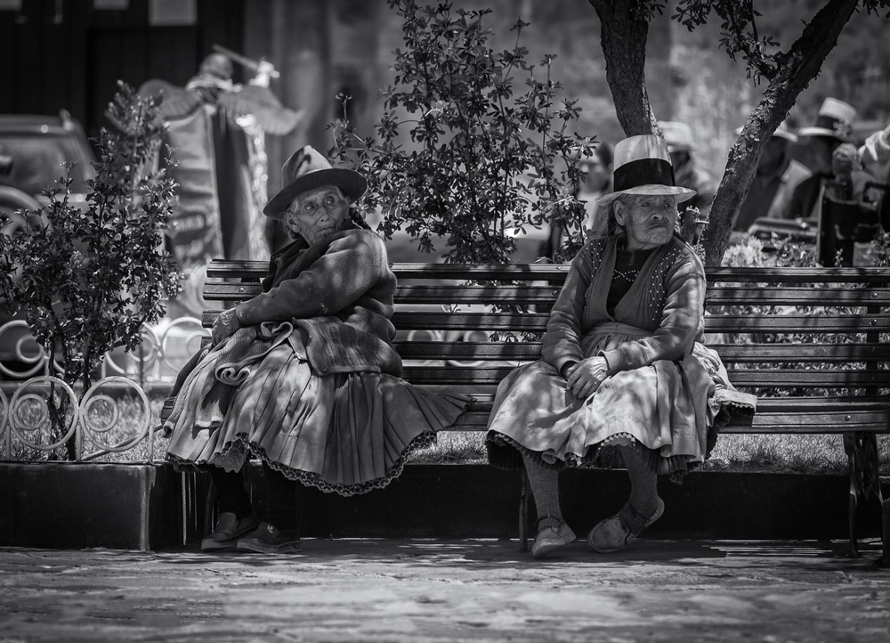   Women in traditional outfit  sitting on a bench in Downtown Cusco.