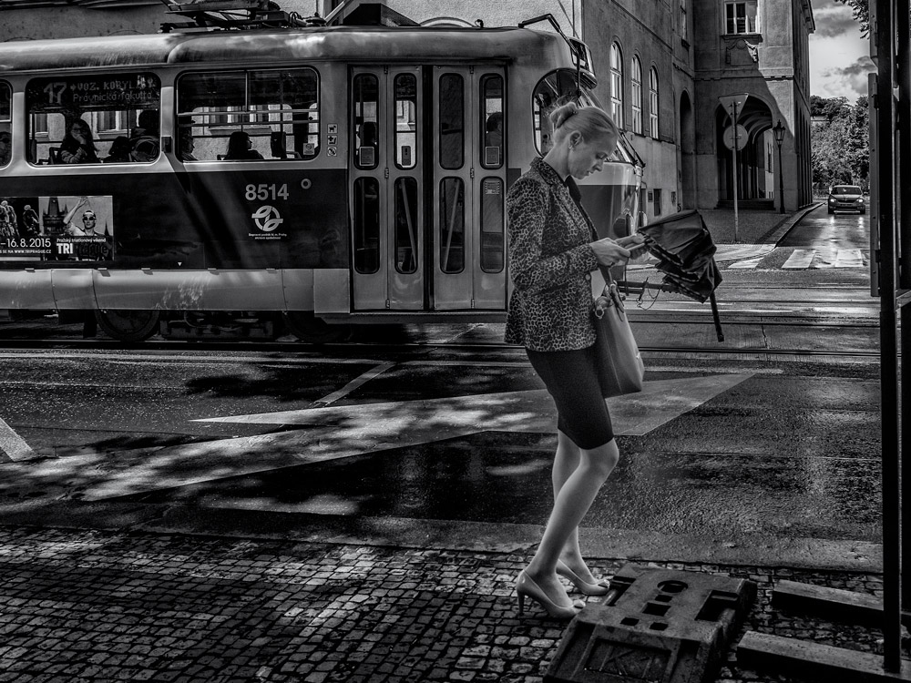 Lady and phone. Lady with a phone waiting for the bus. Sunny day in Prague.  street photography.