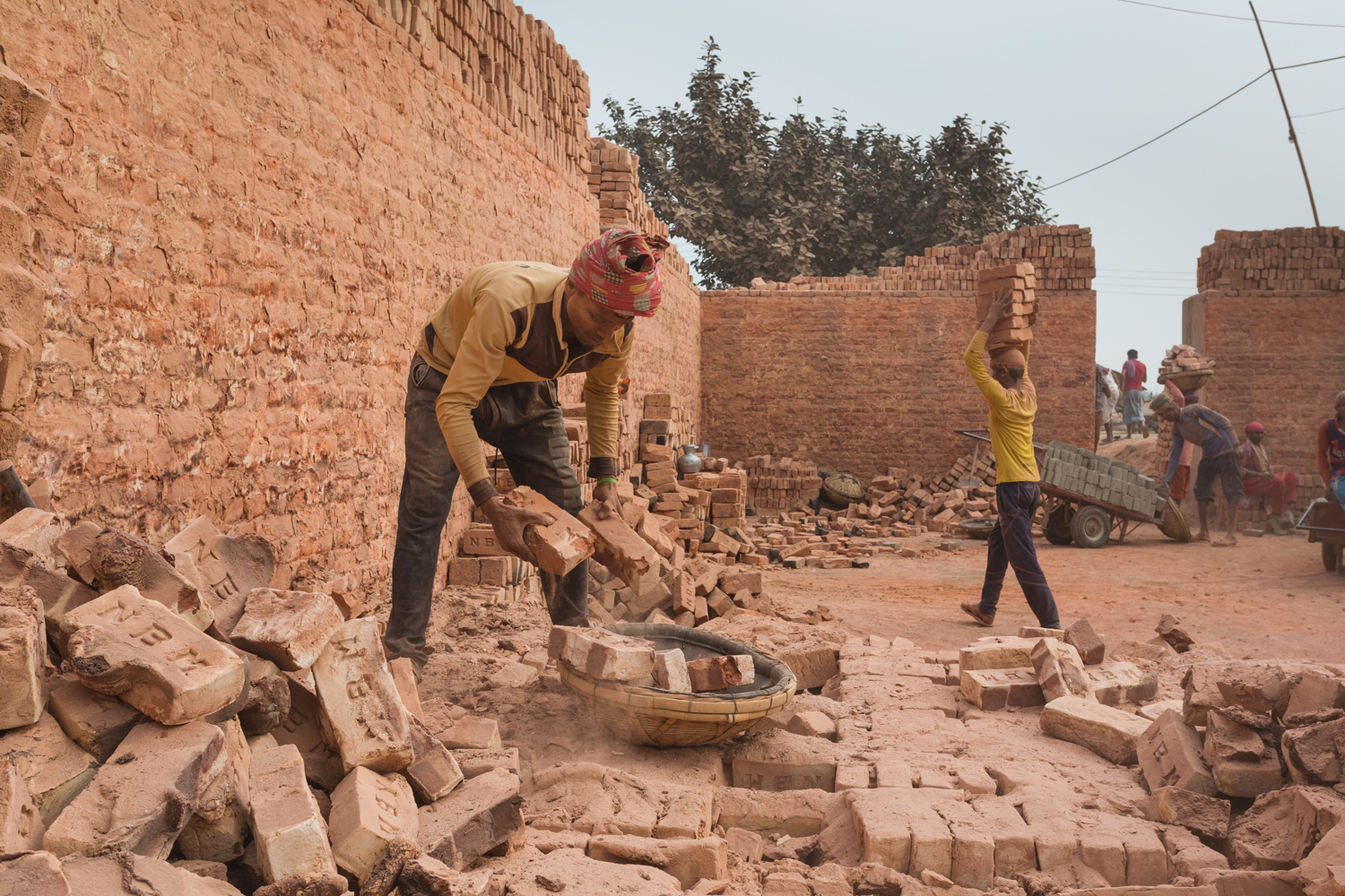 Worker sorting bricks in Chittagong, Bangladesh without protective gear.