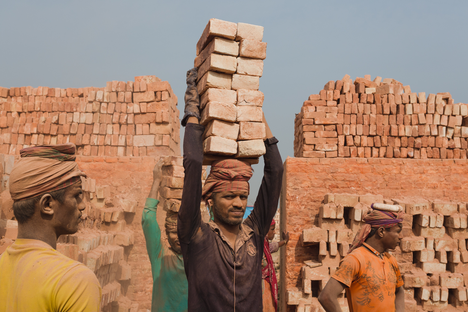 A worker covered by brick dust transporting bricks in Chittagong, Bangladesh.