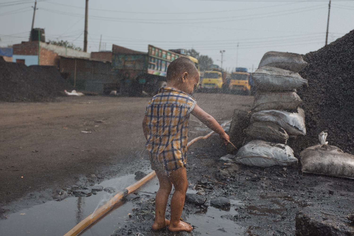 A Dhaka, Bangladesh coal worker child finds something of interest near the huge coal pile.