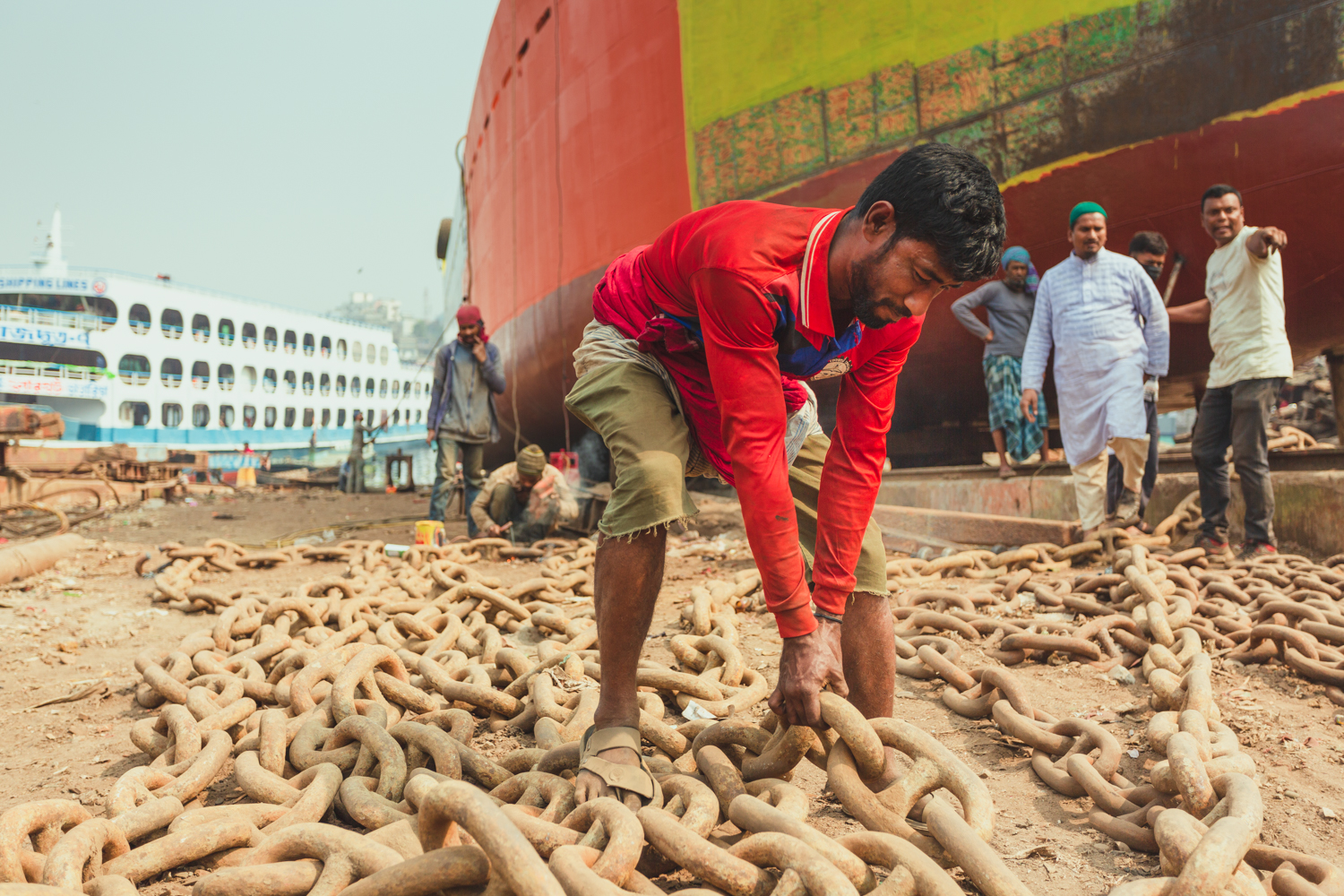 Work struggling to move chains at Dhaka, Bangladesh Shipyard.