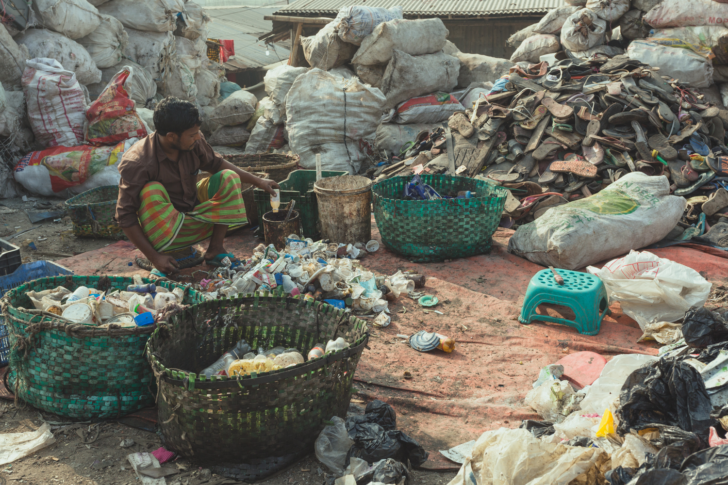 The Waste Pickers of Bangladesh sort rubbish into saleable product piles.