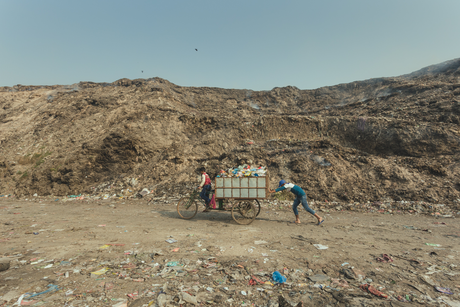 Two boys work together to transport a cart full of collected rubbish in Chittagong, Bangladesh.