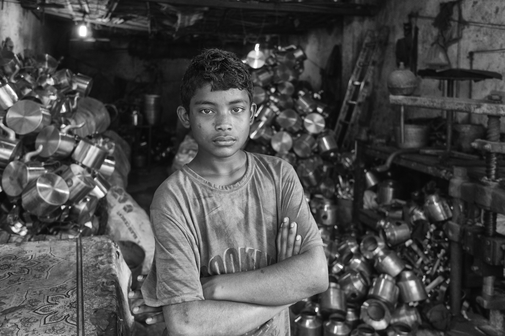 Portrait of child labour, a boy who works in the aluminium pot making factory stands outside during a break, Dhaka, Bangladesh 2020
