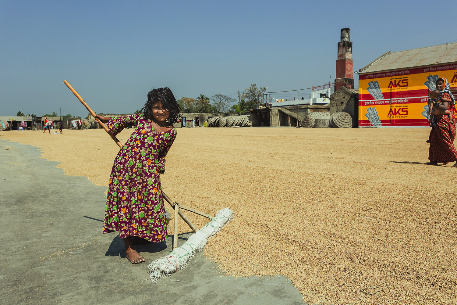 Little girl helping with the ground preparation at Dhaka, Bangladesh Rice Mills.